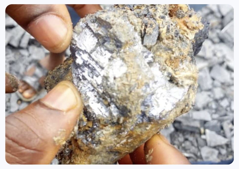 Hands inspecting a raw metallic mineral ore sample