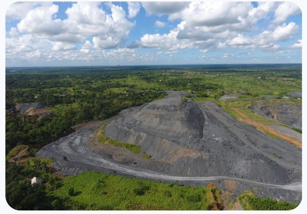 Aerial view of a terraced mining mound surrounded by forest